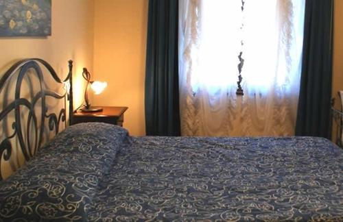 a bedroom with a bed with a blue blanket and a window at B&B La Ca Vecia in Soragna