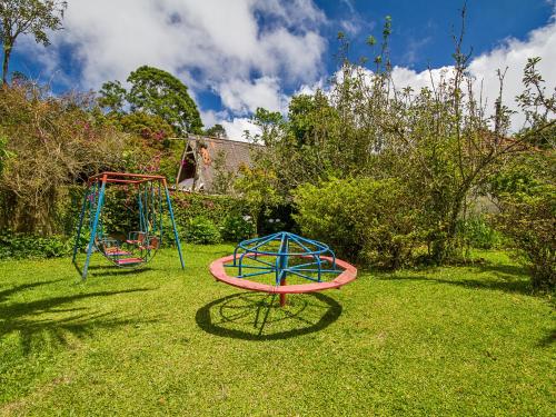 two childrens play equipment on the grass in a yard at Pousada Recanto São Benedito in Campos do Jordão