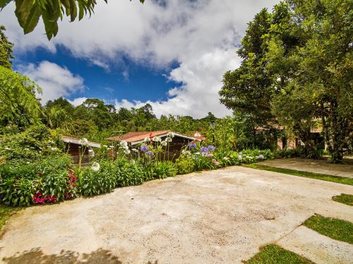 a driveway with flowers and a house in the background at Pousada Recanto São Benedito in Campos do Jordão