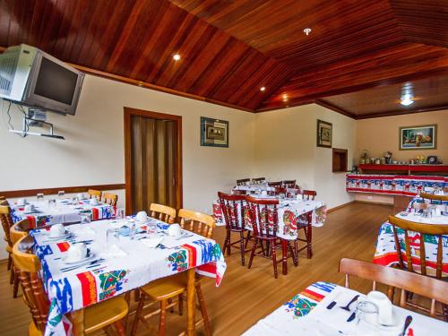 a dining room with tables and chairs and a tv at Pousada Recanto São Benedito in Campos do Jordão