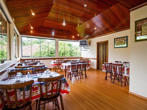 a restaurant with tables and chairs in a room at Pousada Recanto São Benedito in Campos do Jordão