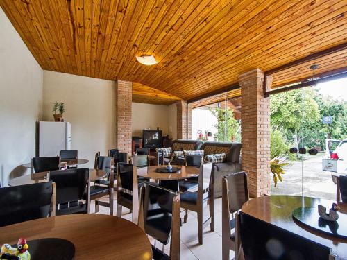 a restaurant with wooden ceilings and tables and chairs at Pousada Recanto São Benedito in Campos do Jordão