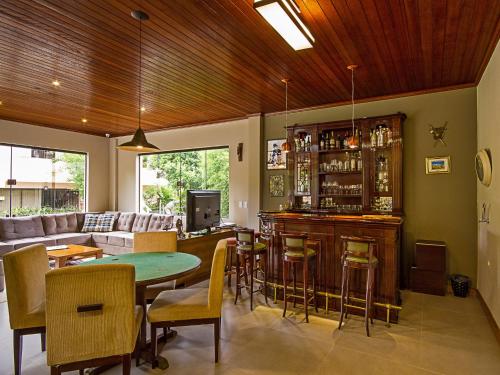 a living room with a bar with a table and chairs at Pousada Recanto São Benedito in Campos do Jordão