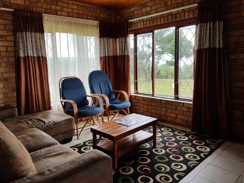 a living room with a couch and chairs and windows at Port Edward Holiday Resort in Port Edward
