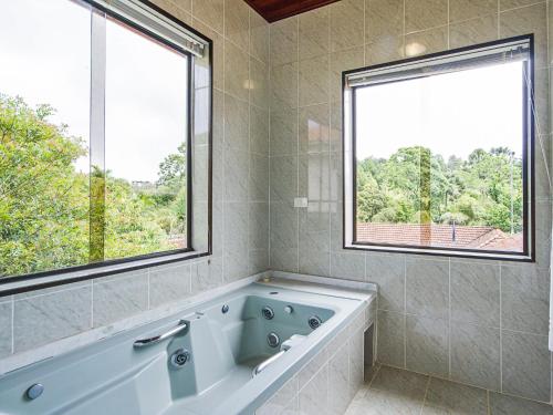 a bathroom with a tub and a large window at Pousada Recanto São Benedito in Campos do Jordão