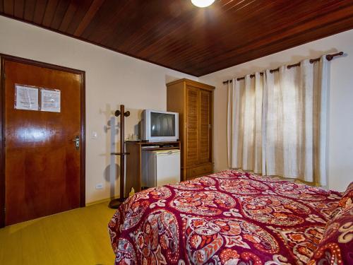 a bedroom with a bed and a television in it at Pousada Recanto São Benedito in Campos do Jordão