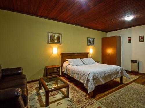 a bedroom with a bed and a couch at Pousada Recanto São Benedito in Campos do Jordão