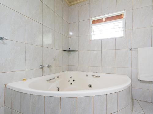 a white bath tub in a white tiled bathroom at Pousada Recanto São Benedito in Campos do Jordão