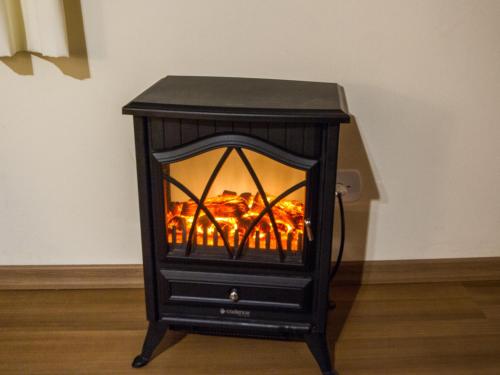 a black stove with a fire inside of it at Pousada Recanto São Benedito in Campos do Jordão