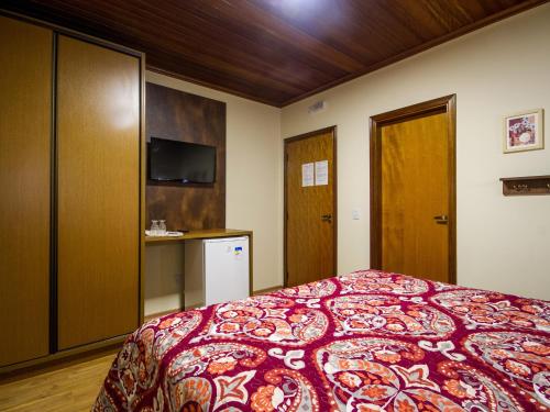 a bedroom with a bed with a red blanket at Pousada Recanto São Benedito in Campos do Jordão