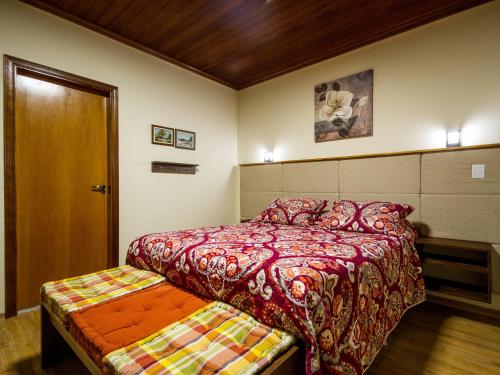 a bedroom with a bed and a wooden door at Pousada Recanto São Benedito in Campos do Jordão