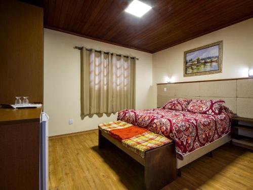 a bedroom with a bed and a bench in it at Pousada Recanto São Benedito in Campos do Jordão