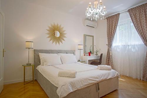 een slaapkamer met een groot bed en een kroonluchter bij Kaleta garden apartment in Split