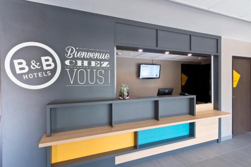 an office lobby with a reception desk with a sign at B&B HOTEL Pau Zénith in Pau