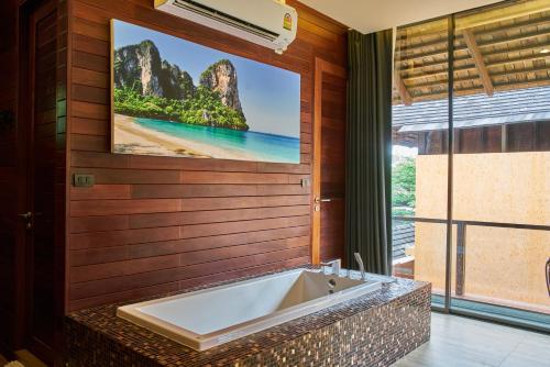 a bathroom with a tub and a large picture of a beach at Avatar Railay in Railay Beach