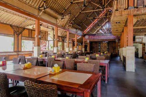 a restaurant with tables and chairs in a building at Hotel Mahkota Plengkung by ecommerceloka in Banyuwangi