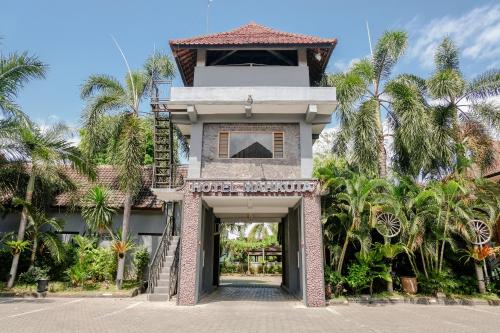 外南夢的住宿－Hotel Mahkota Plengkung by ecommerceloka，一座有楼梯的建筑,通往一座棕榈树建筑