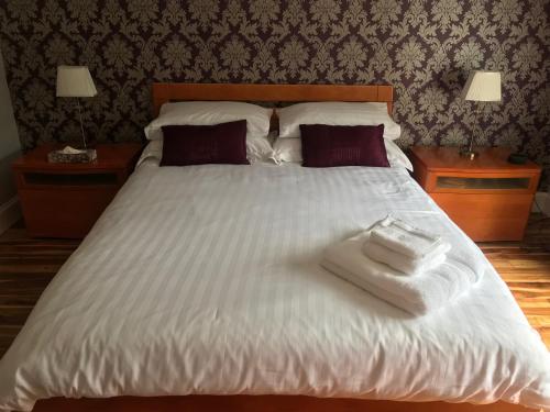 Una cama blanca grande con dos toallas encima. en The Neuk, en Uphall