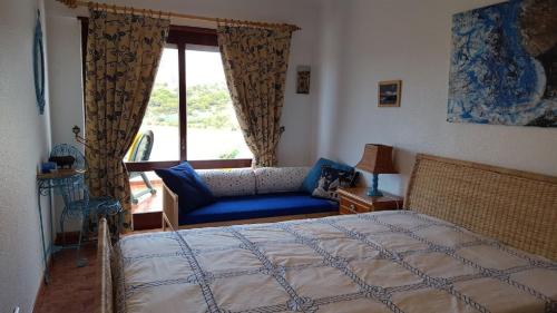 a bedroom with a bed and a couch and a window at Entre o Mar e a Serra in Maceira