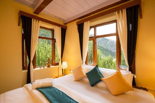 a bedroom with a large bed with two windows at Zostel Homes Rakchham (Kinnaur/Sangla/Chitkul) in Saturang