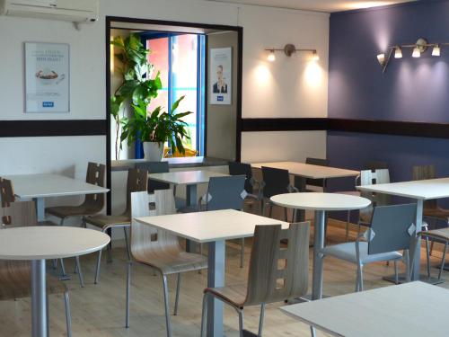 une salle à manger avec des tables et des chaises blanches dans l'établissement Kyriad Toulouse Sud - Roques, à Roques