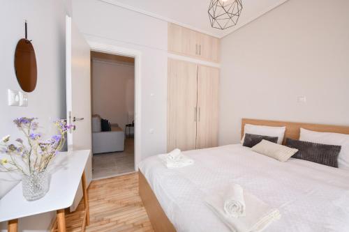 um quarto branco com uma cama e um vaso de flores em Modern, comfortable apartment, in the heart of the city em Lárissa