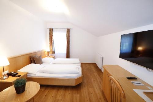 a hotel room with a bed and a flat screen tv at Pension Café Maier in Golling an der Salzach