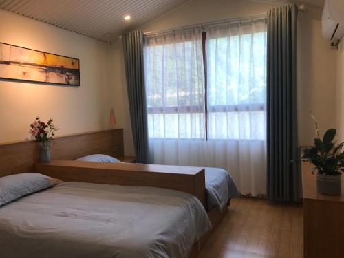 1 dormitorio con 2 camas y ventana en Enshi Grand Canyon Chunlun Farmstay, en Enshi