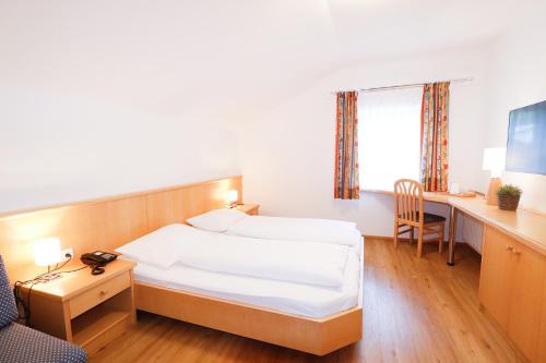 ゴリング・アン・デア・ザルツァッハにあるPension Café Maierのベッドとデスクが備わるホテルルームです。