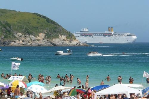 un grupo de personas en una playa con un crucero en Casa temporada próximo a Praia do Forte Cabo Frio c piscina até 10 pessoas incluindo crianças, ligue e confira nossa oferta, en Cabo Frío