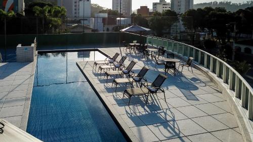 a swimming pool with chairs and tables on a balcony at San Diego Suites Ipatinga in Ipatinga