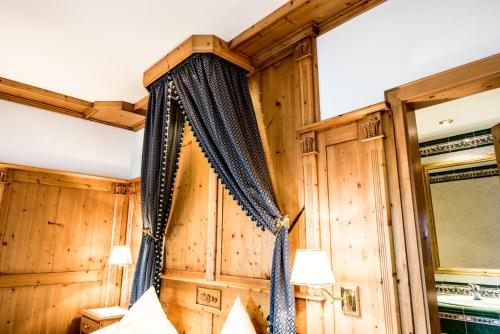 a bedroom with wooden walls and a bed with curtains at Hotel Enzian Genziana in Siusi