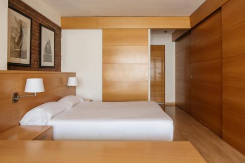 a bedroom with a white bed and wooden cabinets at Wello Apartments in Barcelona