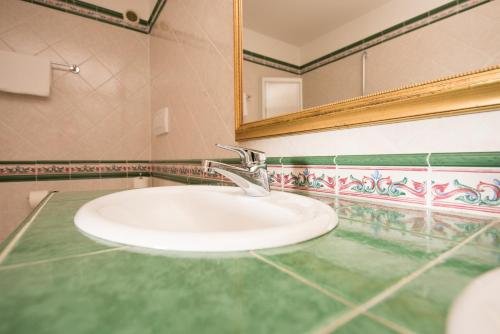 La salle de bains est pourvue d'un lavabo et d'un miroir. dans l'établissement Hotel Enzian Genziana, à Alpe di Siusi
