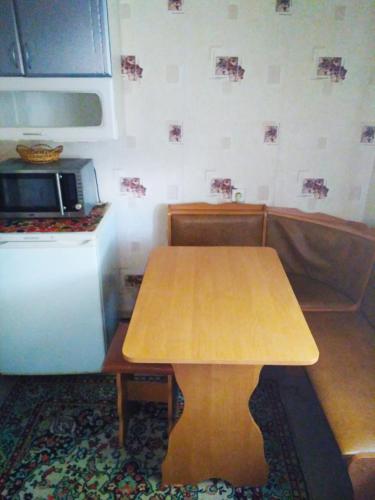 uma pequena cozinha com uma mesa de madeira e um frigorífico em Квартира на Ленина em Okhtyrka