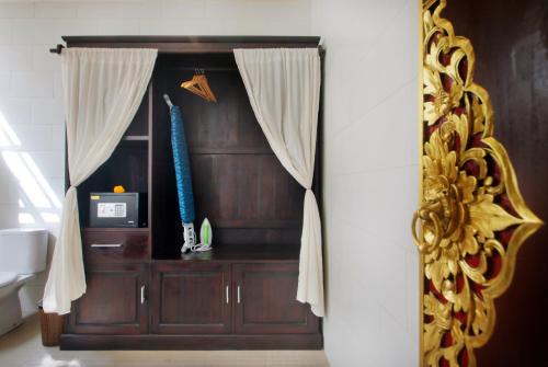 a room with a wooden cabinet with a curtain at Graha Madesimon in Ketewel