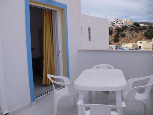 a white table and chairs on a balcony at Mertonas Studios in Karpathos