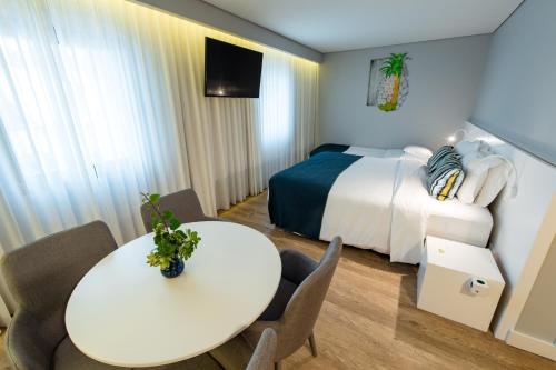 a hotel room with a bed and a table and chairs at Ilha Hostel & Suites in Ponta Delgada
