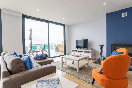 a living room with a couch and chairs and a tv at Apartamento Goncalves in Arco da Calheta