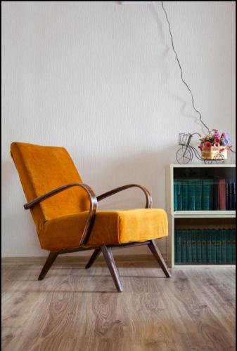 a yellow chair in a room with a book shelf at Your apartment in Old Tbilisi-Ortachala in Tbilisi City