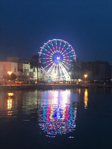 a ferris wheel at night with its reflection in the water at Bernardiniani Apartment in Molfetta