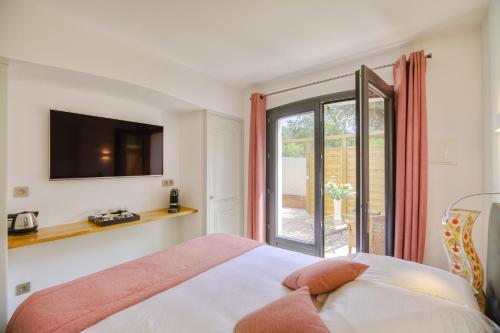 a bedroom with a bed and a tv and a window at Le Refuge - Gigaro Lodges in La Croix-Valmer