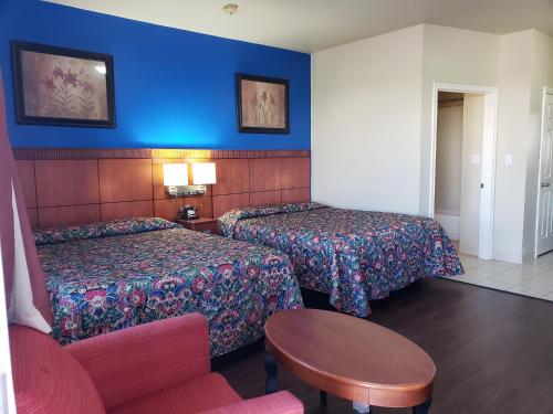 a hotel room with two beds and a table at Crossroads Inn & Suites in Victoria