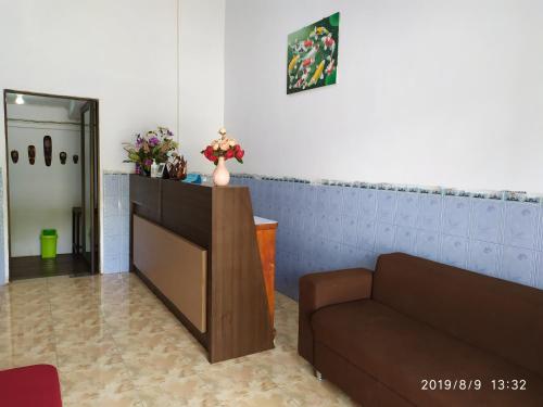 uma sala de espera com um sofá e flores na parede em Penginapan APEX em Dobo