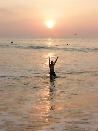 a man sitting in the water in the ocean at sunset at Hotel OBEGA PACIFIC in Nuquí