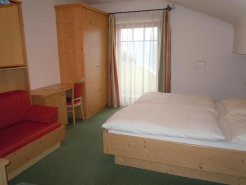 a bedroom with a bed and a chair and a window at Haus Heigl in Sankt Johann im Pongau