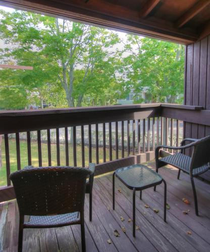 two chairs and a table on a porch with a window at Aspinquid Resort in Ogunquit