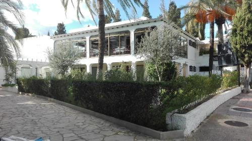a white house with palm trees in front of it at Apartamento con vistas al puerto deportivo Las Fuentes in Alcossebre