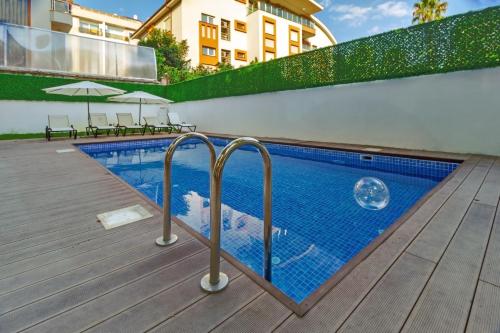 a swimming pool with blue tiles on a wooden deck at Aspendos eXtra in Antalya