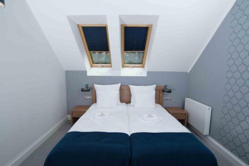 a bedroom with a blue and white bed with two windows at Hudson in Koszalin